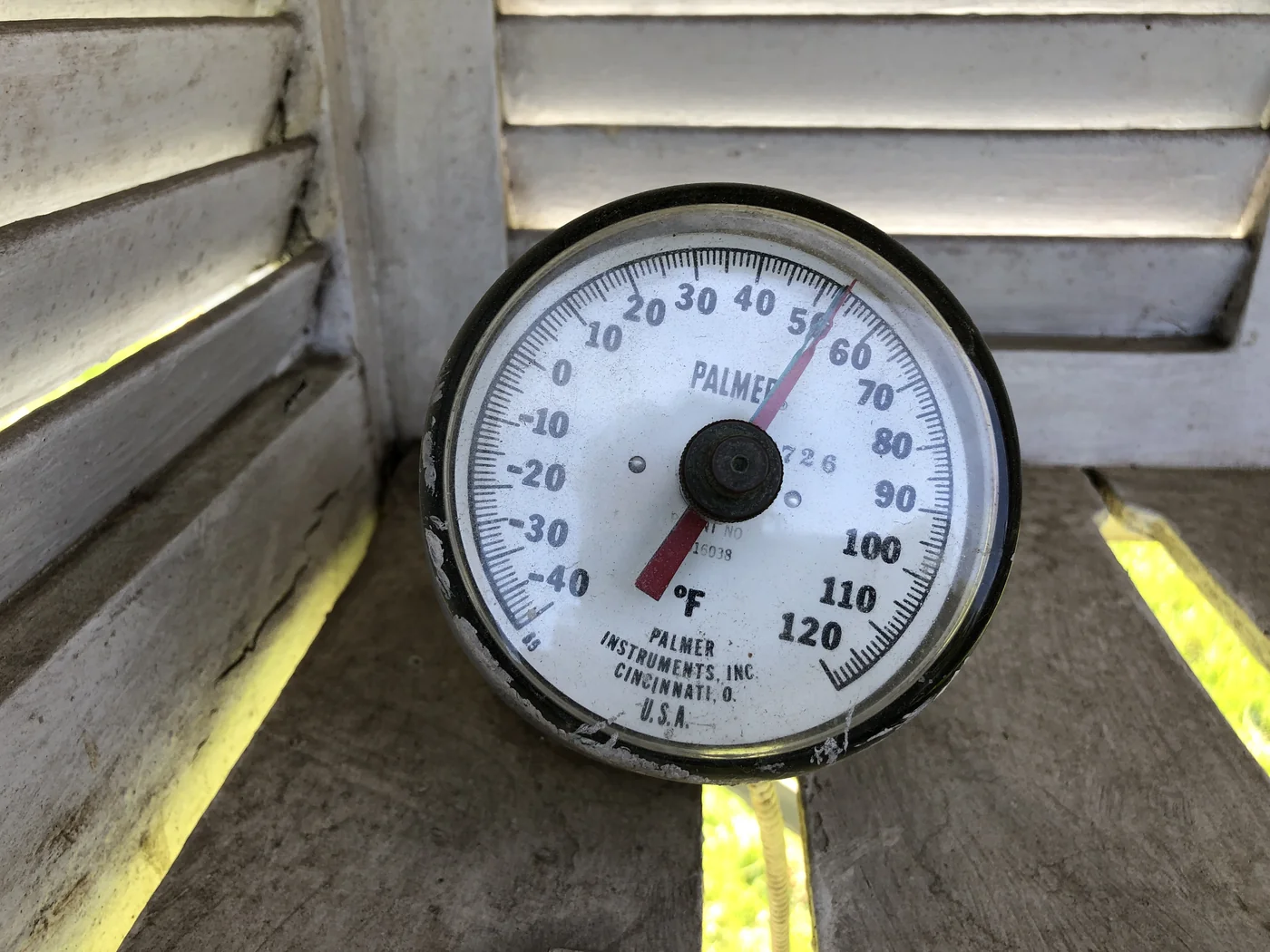 Stainless steel dial soil thermometer inserted 4 inches into garden soil reading 65 degrees Fahrenheit