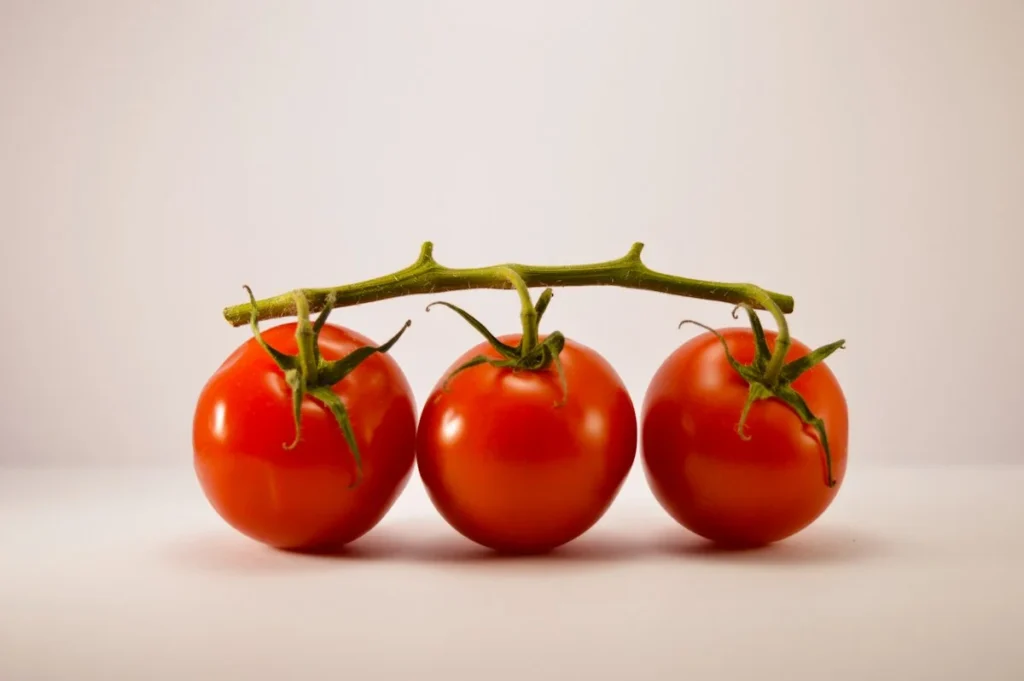 Fresh harvest bowl of glossy ripe Orange Hat cherry tomatoes with cross section showing thin skin and seed cavity